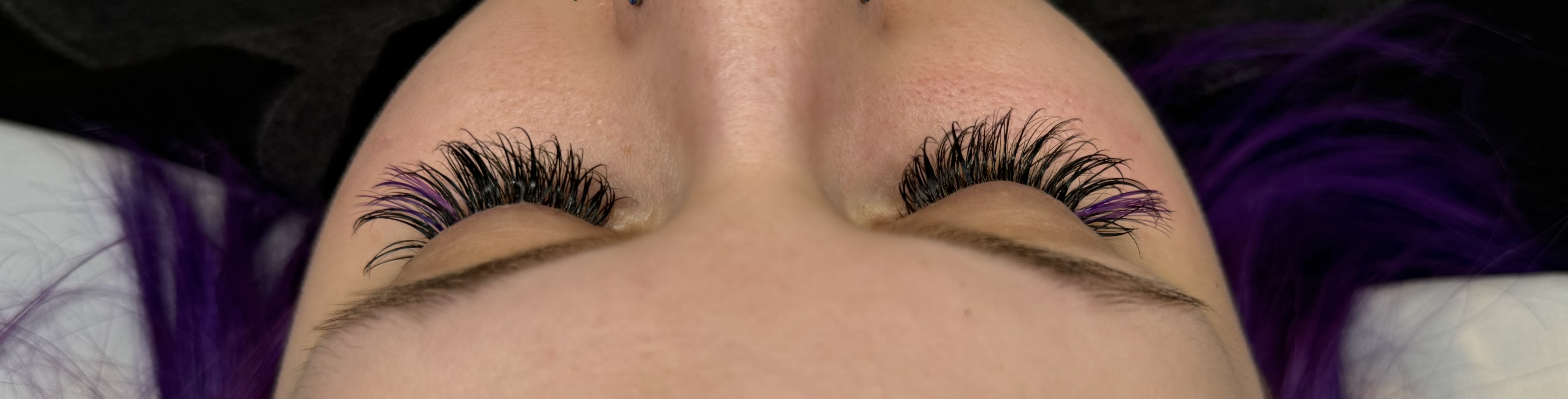 Wispy hybrid eyelash extensions with a subtle purple accent