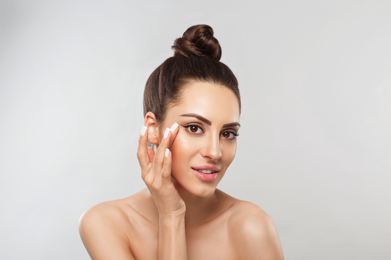 Beautiful Woman with healthy smooth facial clean skin holding bottle cosmetic cream. Face Skin care Moisturizer Facial treatment. Cosmetology. Dermaplane facial. Spa